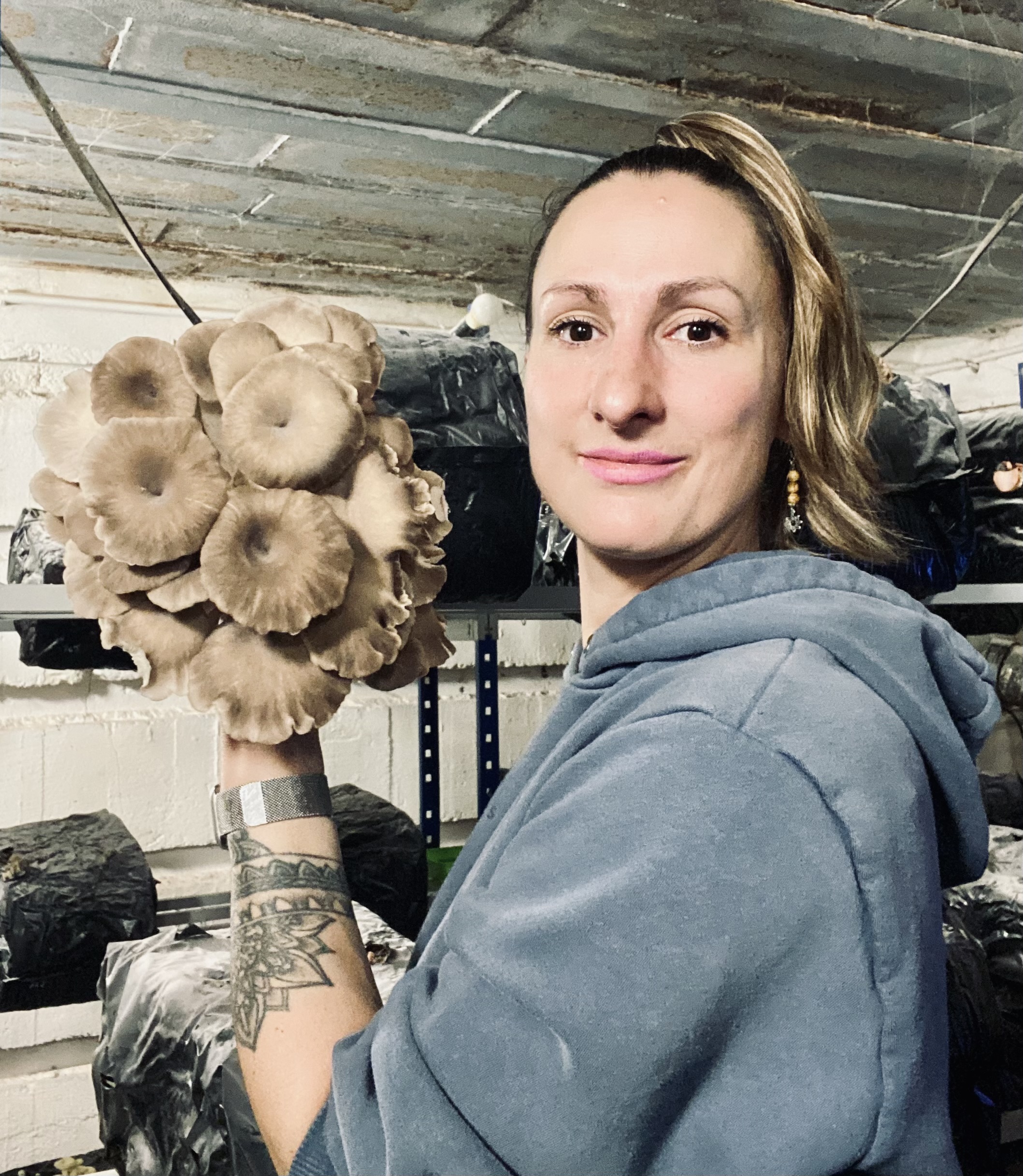 Julie à l'intérieur du blockhaus présentant une grappe de pleurotes gris à la main